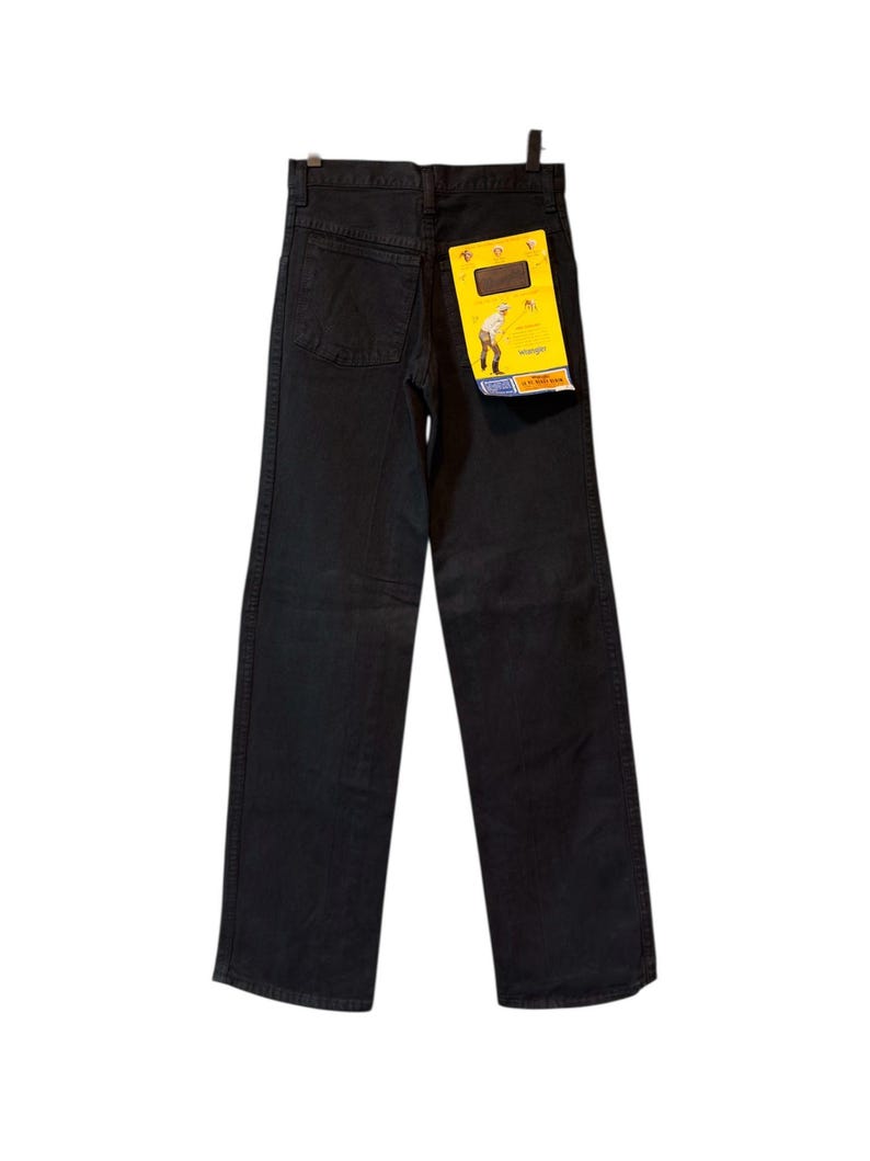 K&ouml;nnte beinhalten: Schwarze Jeans aus Denim mit geradem Bein. Die Jeans haben ein klassisches F&uuml;nf-Taschen-Design und ein gelbes Etikett an der Ges&auml;&szlig;tasche. Das Etikett zeigt eine Grafik und den Markennamen.