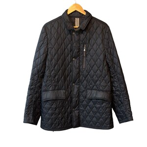 May include: A black quilted jacket with a button-down front, two front pockets, and a small zippered chest pocket. The jacket is hanging on a wooden hanger against a white background. The jacket has a diamond pattern.