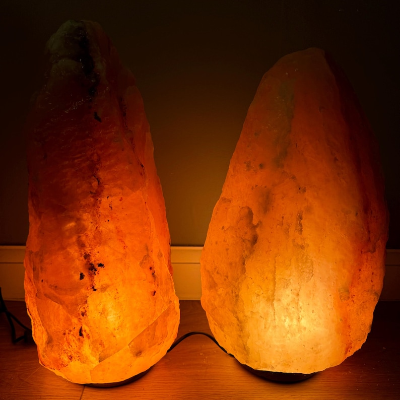 May include: Two large, orange Himalayan salt lamps with warm, glowing light. The lamps are made of natural salt crystals and are illuminated from within.