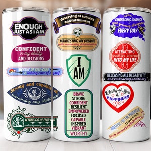 Könnte beinhalten: Drei weiße Becher mit motivierenden Zitaten und Grafiken. Die Becher zeigen Sätze wie "Genug, so wie ich bin", "Ich bin", "Würdig der Liebe & des Glücks" und "Dankbar für den Fortschritt".