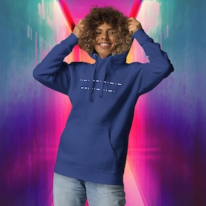 Puede incluir: Una sudadera con capucha azul marino con un gráfico blanco de una serie de guiones en la parte delantera. La sudadera con capucha tiene una capucha con cordón y un bolsillo canguro.