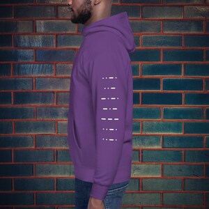 Peut inclure: Un sweat à capuche violet avec un motif blanc de tirets sur la manche gauche.