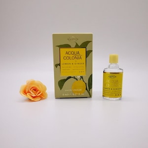 Puede incluir: Una pequeña botella de 4711 Acqua Colonia Lemon & Ginger Eau de Cologne. La botella es de vidrio transparente con una etiqueta amarilla y una tapa amarilla. La botella está sobre una superficie blanca.