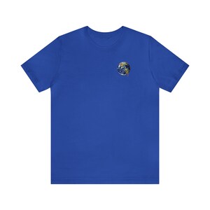 Può includere: Una t-shirt blu reale con una piccola grafica rotonda e colorata della Terra sul petto sinistro.