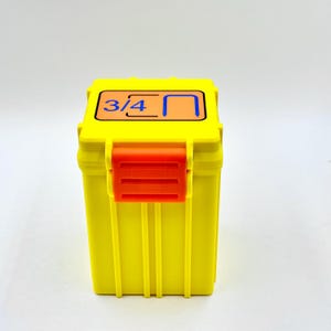 May include: A yellow plastic storage box with an orange latch. The lid has a label with the text "3/4" and a graphic of a U-shaped bracket.