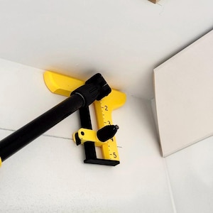 May include: A yellow and black tool for measuring angles and distances. The tool has a ruler marked with numbers 1 through 5. The tool is attached to a black pole.
