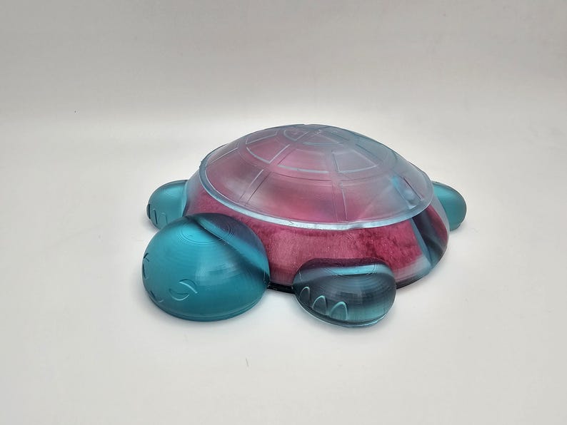 May include: A blue and clear plastic turtle shaped soap dish. The dish has a pink interior.