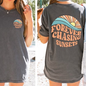 May include: A gray oversized t-shirt with a graphic of a sunset and waves. The text "FOREVER CHASING SUNSETS" is printed in a retro font.