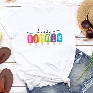 May include: White t-shirt with the text "hello summer" and colorful popsicle graphics.