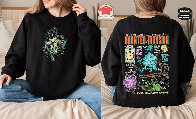 May include: Black sweatshirt with a colorful graphic print of the Haunted Mansion attraction at Disneyland. The print features the text "The Welcome Foolish Mortals Haunted Mansion 999 Happy Haunts" and various characters from the attraction.