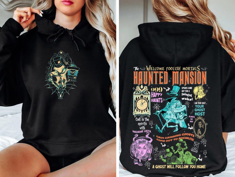 May include: Black hooded sweatshirt with a graphic print of the Haunted Mansion attraction from Disneyland. The print features the text "The Welcome Foolish Mortals Haunted Mansion" with a clock, ghosts, and the text "999 Happy Haunts".