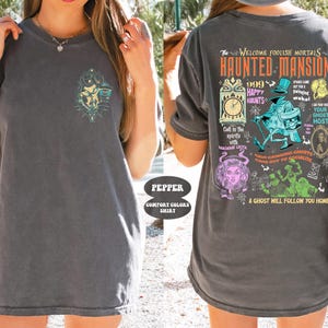 May include: A gray t-shirt with a graphic print of the Haunted Mansion attraction at Disneyland. The graphic includes the text "The Welcome Foolish Mortals Haunted Mansion", "999 Happy Haunts", "Your Ghost Host", and "A Ghost Will Follow You Home".