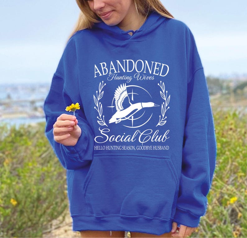 May include: Royal blue hoodie with the text "ABANDONED Hunting Wives Social Club" and a graphic of a flying duck. The text "HELLO HUNTING SEASON, GOODBYE HUSBAND" is also printed on the hoodie.