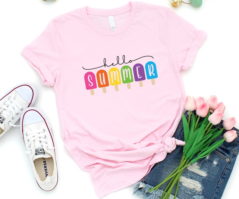 May include: Pink t-shirt with the text "hello summer" in black script with rainbow popsicle graphics.