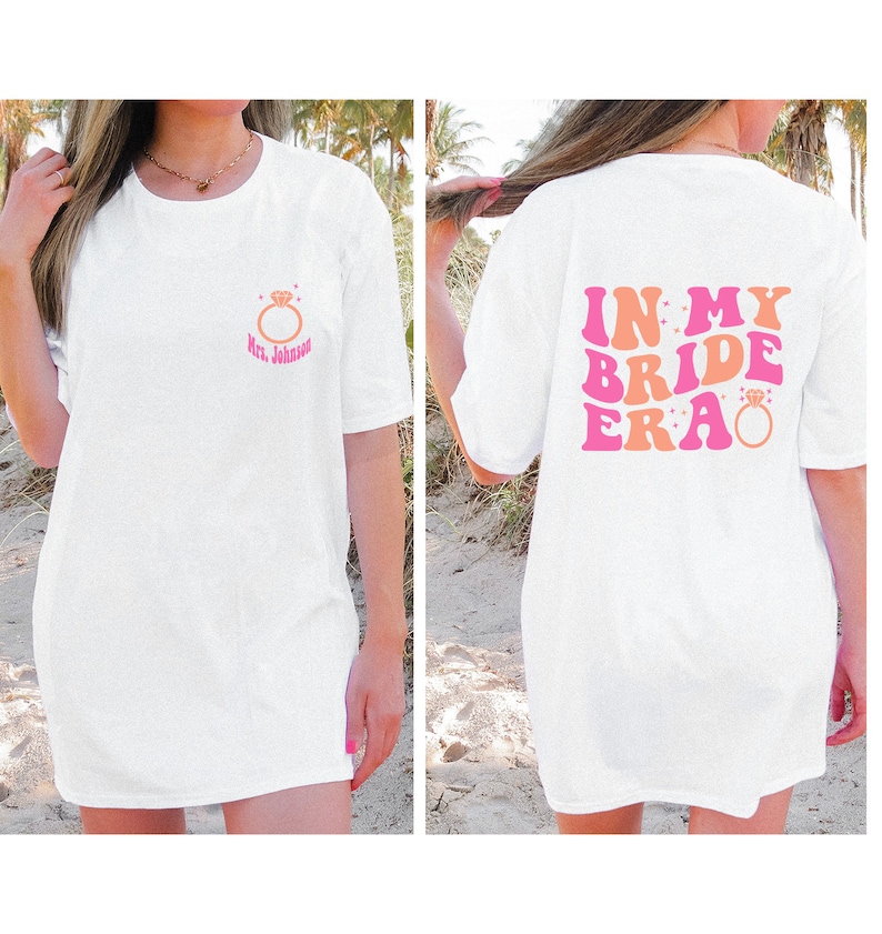 May include: White t-shirt with a pink and orange graphic that says "In My Bride Era" with a diamond ring graphic. The front of the shirt has a small diamond ring graphic with the text "Mrs. Johnson".