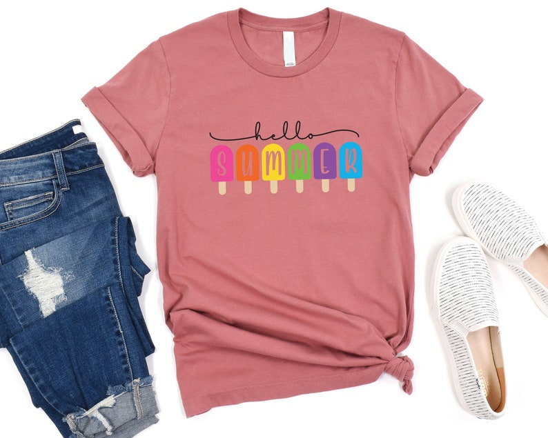 May include: A dusty rose t-shirt with the text "hello summer" in black lettering. The text is decorated with a row of colorful popsicles.