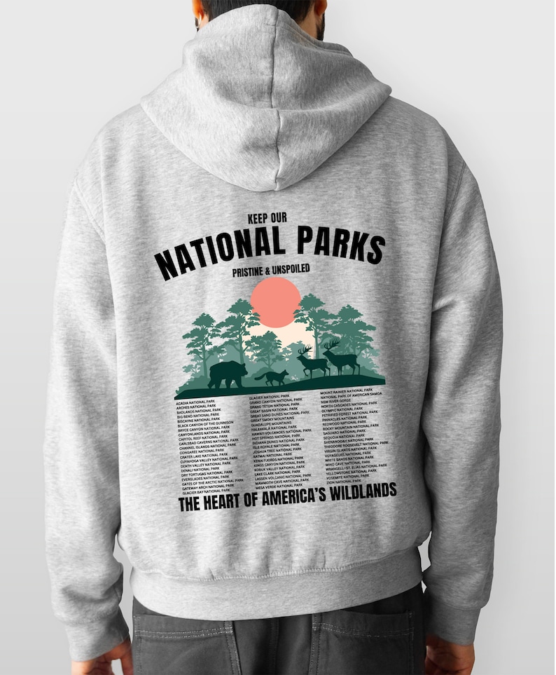 May include: Gray hooded sweatshirt with a graphic print of a forest scene and the text "Keep Our National Parks Pristine & Unspoiled". The graphic also includes a list of national parks in the United States. The text "The Heart of America's Wildlands" is printed below the list.