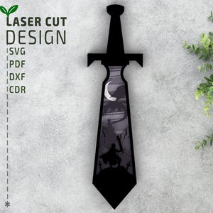 May include: Black laser-cut design of a sword with a detailed interior scene. The scene depicts a silhouette of a figure holding a sword, a castle, and a crescent moon. The text "LASER CUT DESIGN" and file type options are visible.