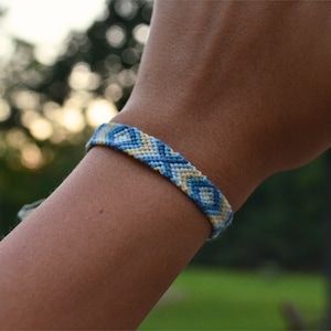 May include: A blue and white friendship bracelet with a diamond pattern.