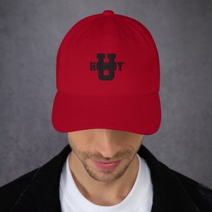 Puede incluir: Gorra de béisbol roja con un logotipo bordado en negro "Howdy U".