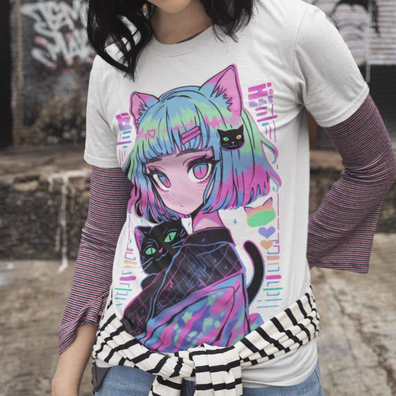 May include: A white t-shirt with a colorful graphic print of an anime-style girl with cat ears and a black cat. The girl has blue and pink hair and is wearing a black and white outfit. The graphic is surrounded by a rainbow-colored border.