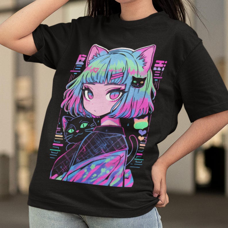 May include: Black t-shirt with a colorful graphic print of a girl with cat ears and two cats. The girl has pink and blue hair and is wearing a black and white patterned shirt. The text "litch" is printed on the shirt.