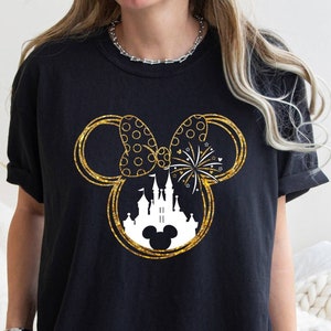May include: Black t-shirt with a gold glitter Mickey Mouse silhouette featuring a white castle and fireworks inside the ears.