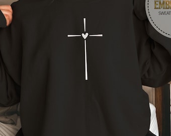 May include: Black sweatshirt with a white embroidered cross and heart design. The sweatshirt is a comfortable and casual style.