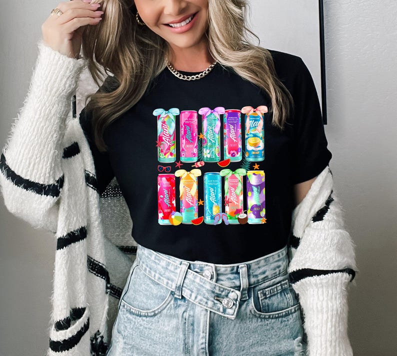 Peut inclure: T-shirt noir avec un motif color&eacute; de canettes de boisson &eacute;nergisante Alani Nu. Chaque canette pr&eacute;sente un design et une saveur diff&eacute;rents. Le t-shirt est &agrave; col rond et de style d&eacute;contract&eacute;.