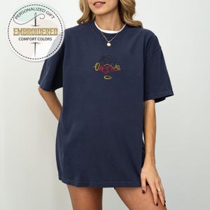 May include: A navy blue oversized t-shirt with a red, yellow, and black embroidered design of Mickey Mouse.