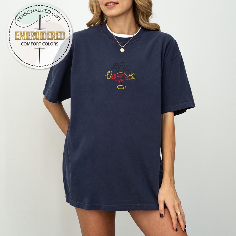 May include: A navy blue oversized t-shirt with a red, yellow, and black embroidered design of Mickey Mouse.