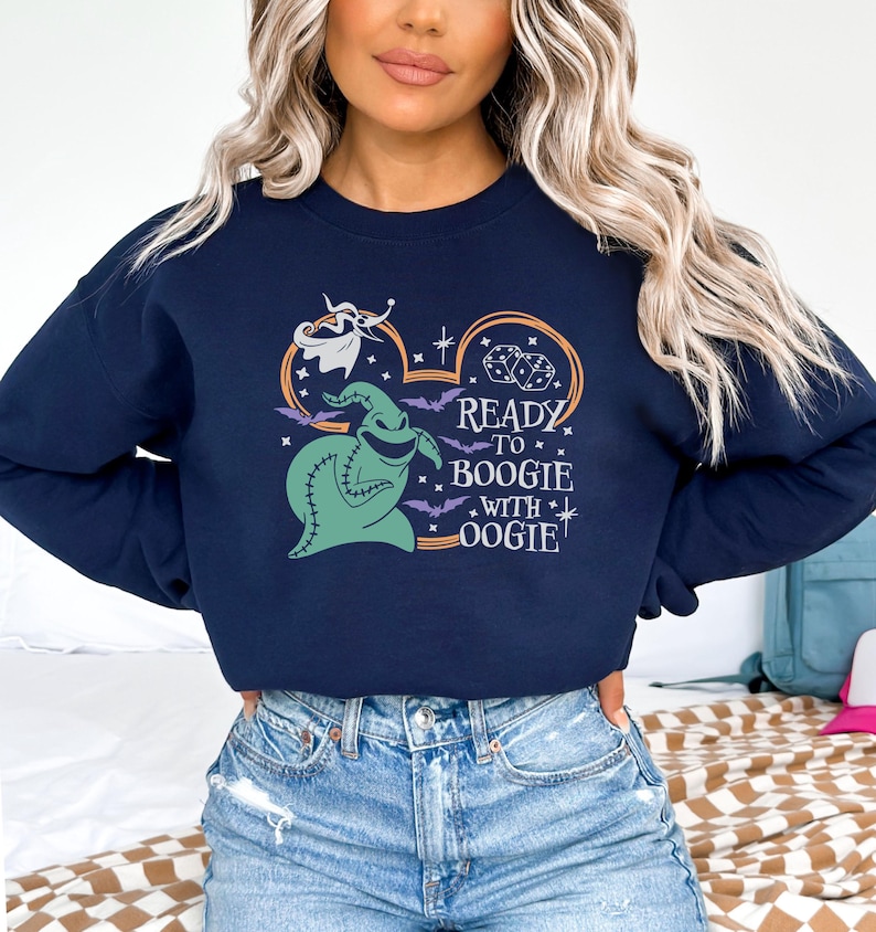 Pu&ograve; includere: Felpa blu navy con una grafica di Oogie Boogie, dadi e pipistrelli, con la scritta "Ready to Boogie with Oogie!". Il disegno &egrave; racchiuso in un contorno di orecchio di Topolino. Un top comodo e casual per Halloween o per i fan Disney.