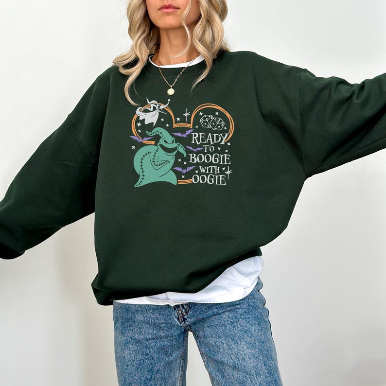 Pu&ograve; includere: Felpa verde scuro con una grafica di Oogie Boogie da The Nightmare Before Christmas. Il design include il testo "Ready to Boogie with Oogie", pipistrelli e stelle. La felpa &egrave; uno stile casual e confortevole.