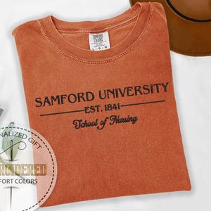 May include: A burnt orange t-shirt with black embroidery that reads "Samford University - Est. 1841 - School of Nursing".
