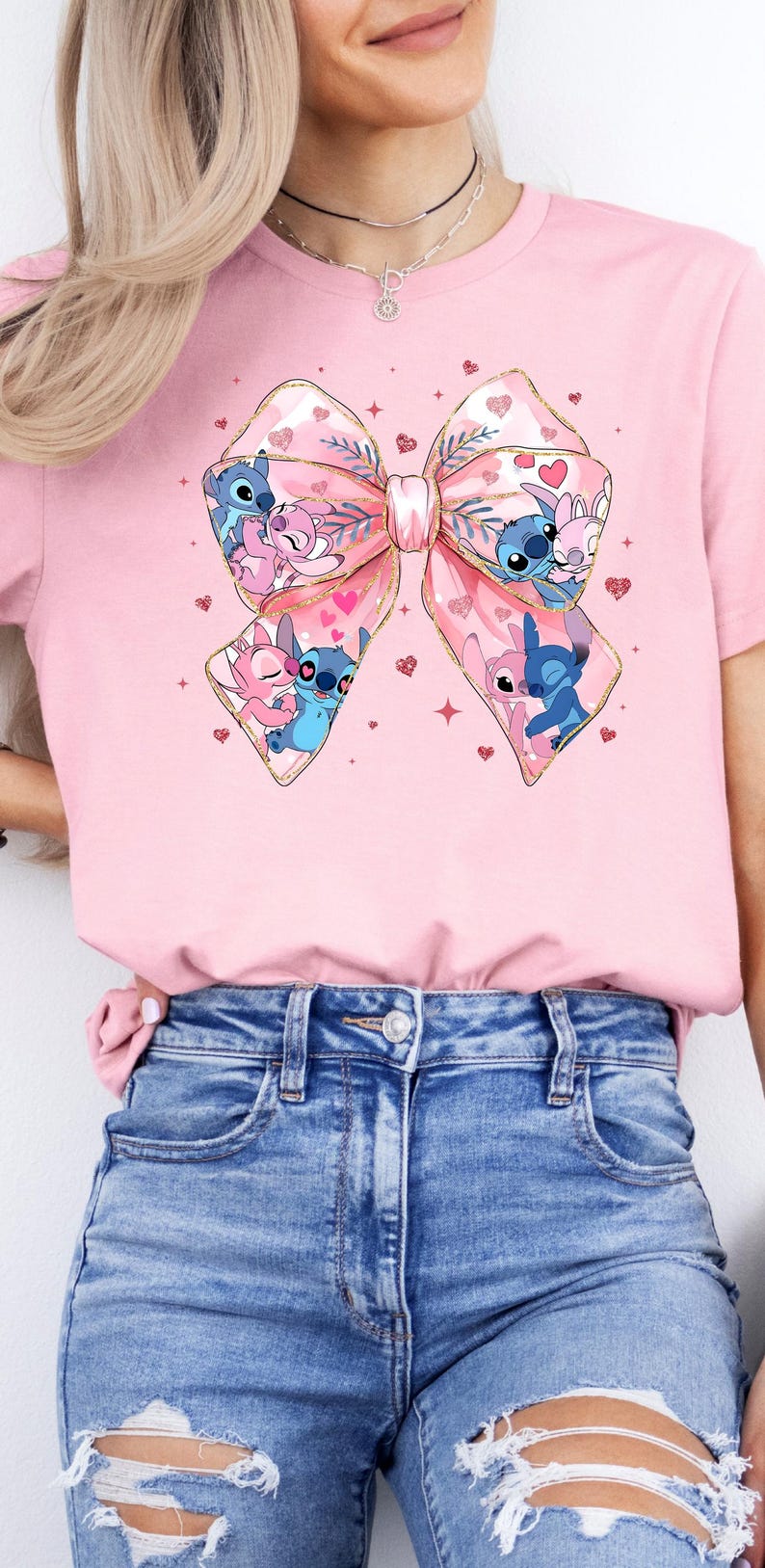 May include: Pink t-shirt with a large pink bow featuring a cartoon couple of Stitch and Angel. The bow is decorated with gold glitter and hearts.