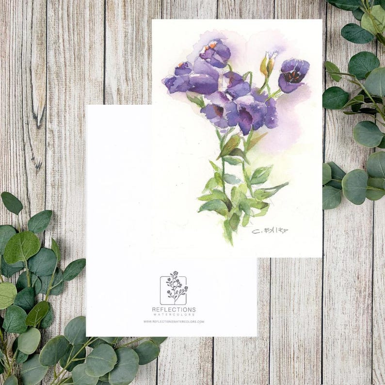 May include: A watercolour greeting card displaying a cluster of purple flowers with green foliage. The card includes the text "Reflections Watercolours" and a website address. The artwork is signed by the artist.