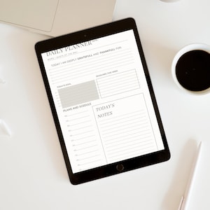 Op de afbeelding: Een dagelijkse planner op een tablet met de tekst "Daily Planner" en "Self Love Journey". De planner heeft secties voor "Word/Quote of the Day", "Today I am deeply grateful and thankful for", "Today's Goal", "Deadlines this week", "Plans and Schedule" en "Today's Notes".