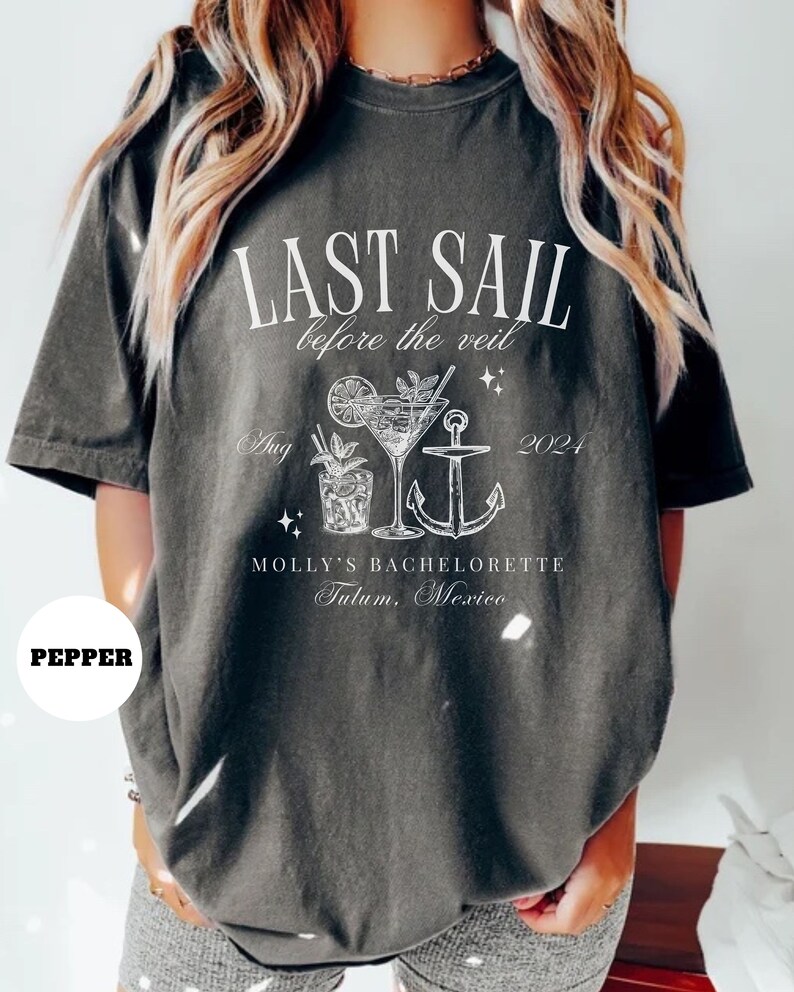 May include: A gray t-shirt with white text that reads "Last Sail Before the Veil" with a cocktail and anchor graphic. The text also includes "Aug 2021" and "Molly's Bachelorette Tulum, Mexico".