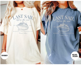 May include: Two t-shirts with the text "Last Sail Before the Veil" and a cruise ship graphic. The shirt on the left is ivory and the shirt on the right is blue jean.