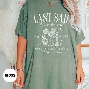 May include: Green oversized t-shirt with white text that reads "Last Sail Before the Veil" with a cocktail and anchor graphic. The text also includes "Aug 2021" and "Molly's Bachelorette Tulum, Mexico".