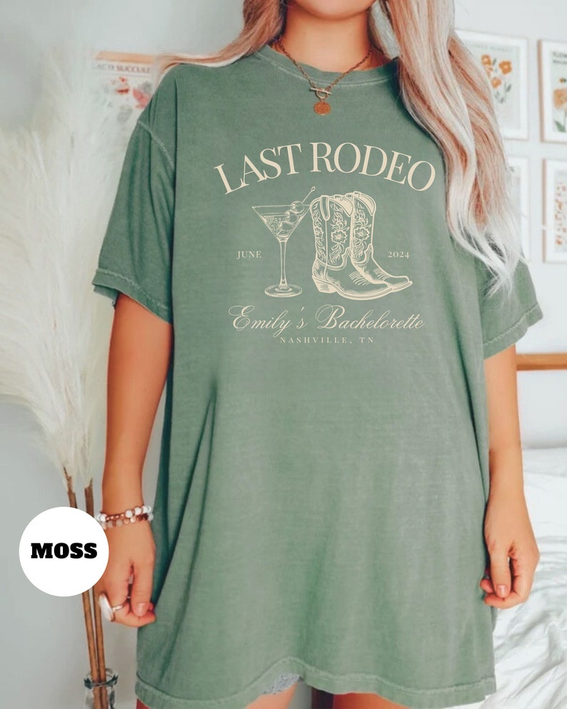 May include: A green t-shirt with the text "LAST RODEO" printed on the front. The text is in white and is surrounded by a drawing of a pair of cowboy boots and a martini glass. The text "JUNE 2024" is printed below the boots and the text "Emily's Bachelorette NASHVILLE, TN" is printed below the martini glass.