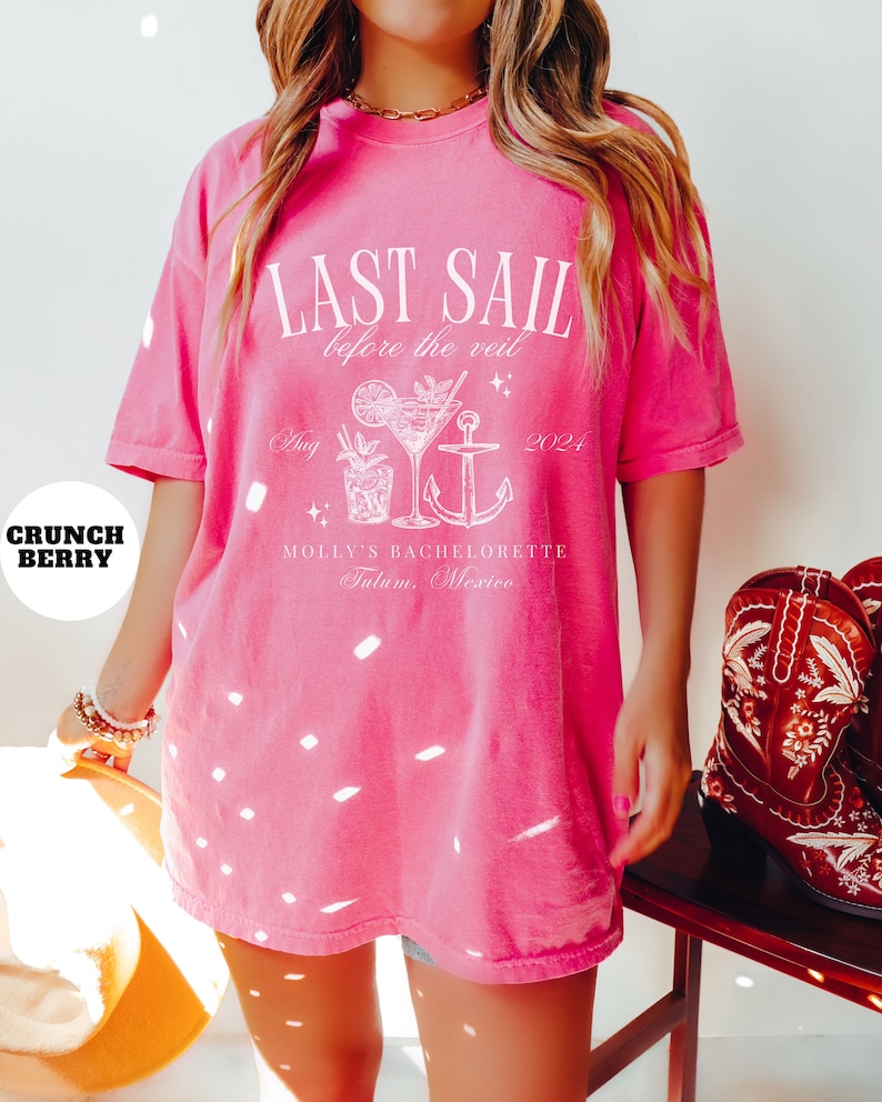 May include: Pink oversized t-shirt with white text that reads "Last Sail Before the Veil" with a cocktail and anchor graphic. The text also includes "Aug 2024 Molly's Bachelorette Tulum, Mexico".