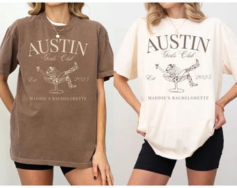 May include: Two brown and white t-shirts with a graphic design of a woman sitting in a martini glass. The text on the shirts reads "Austin Girls Club Est 2025 Maddie's Bachelorette".