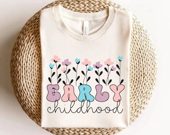 May include: A white t-shirt with a graphic design of colorful flowers and the text "EARLY childhood" in a whimsical font.