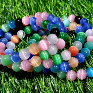 May include: A set of colorful bracelets made with round, iridescent beads. The beads are in shades of blue, green, pink, and white.