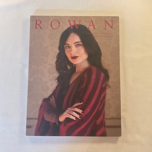 May include: A magazine cover featuring a woman wearing a red and black striped sweater. The magazine is titled "Rowan Knitting & Crochet" and the issue number is 64.