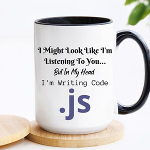 Peut inclure: Une tasse en c&eacute;ramique blanche avec un bord et une poign&eacute;e noirs. La tasse pr&eacute;sente un motif de texte noir et blanc qui se lit comme suit : "I Might Look Like I'm Listening To You... But In My Head I'm Writing Code .js".
