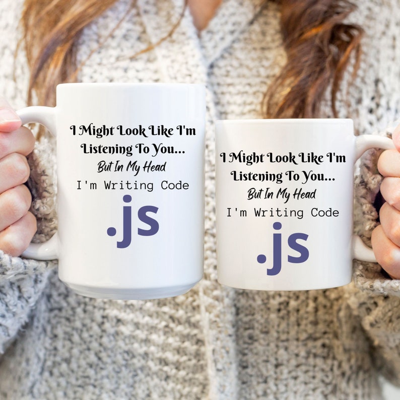 Peut inclure: Deux tasses blanches avec du texte noir et un logo .js violet. Le texte sur les tasses est "I Might Look Like I'm Listening To You... But In My Head I'm Writing Code".