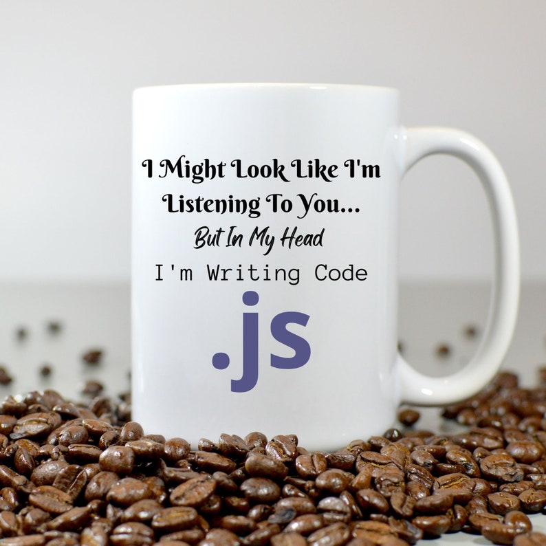 Peut inclure: Une tasse &agrave; caf&eacute; en c&eacute;ramique blanche avec du texte noir qui dit "I Might Look Like I'm Listening To You... But In My Head I'm Writing Code .js". Le texte .js est en violet.