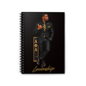 May include: A black spiral-bound notebook featuring a graphic of a person in a black suit with a gold and black striped tie. The design includes the Greek letters Alpha Phi Alpha in a gold vertical rectangle and the word Leadership in gold script.